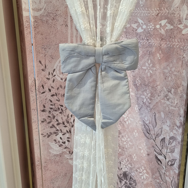Fermatenda shabby chic formato da fascia con velcro e fiocco imbottito di colore grigio. Vista frontale